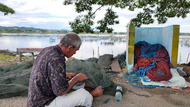 Nazaruddin Razali, nelayan yang mengajukan permohonan suntik mati, sedang memperbaiki jaring keramba di Waduk Pusong, Lhokseumawe, Kamis (6/1/2022). Foto: Dedy Syahputra/ANTARA