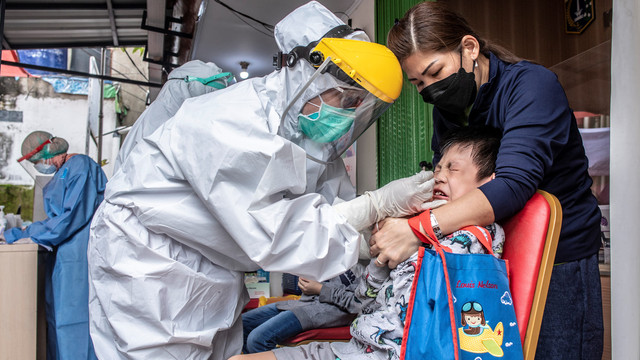 Petugas kesehatan melakukan tes usap COVID-19 kepada seorang bocah saat tes massal di Kelurahan Krukut, Kecamatan Taman Sari, Jakarta Barat, Senin (10/1/2022). Foto: Muhammad Adimaja/Antara Foto