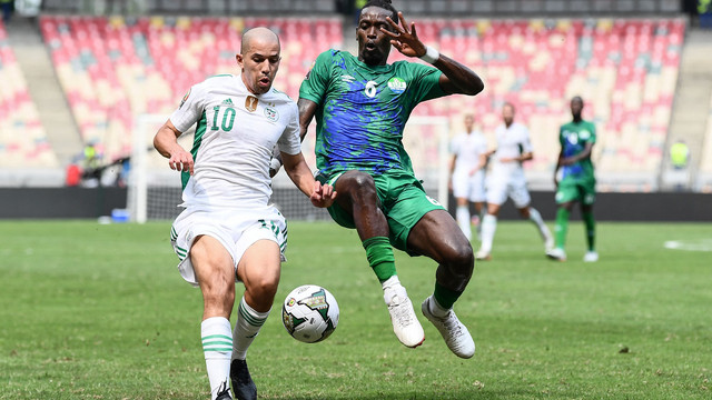 Pemain Aljazair Sofiane Feghouli duel dengan pemain Sierra Leone John Kamara saat pertandingan Grup E Piala Afrika 2021 di Stade de Japoma di Douala, Selasa (11/1/2022). Foto: Charly Triballeau/AFP
