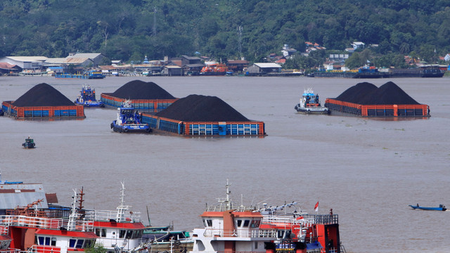 Tumpukan batu bara terlihat diangkut dengan tongkang di Samarinda, Kalimantan Timur, Selasa (11/1). Foto: AKSARA M. RAHMAN/AFP