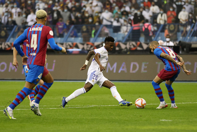 Pemain Real Madrid Vinicius Junior berusaha melewati pemain FC Barcelona Dani Alves pada pertandingan Piala Super Spanyol di Stadion Internasional King Fahd, Riyadh, Arab Saudi. Foto: Albert Gea/REUTERS
