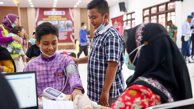 Petugas vaksinasi (vaksinator) memeriksa kesehatan seorang anak sebelum menerima suntik vaksin COVID-19 Sinovac di Museum Aceh, Kamis (13/1). Foto: Suparta/acehkini