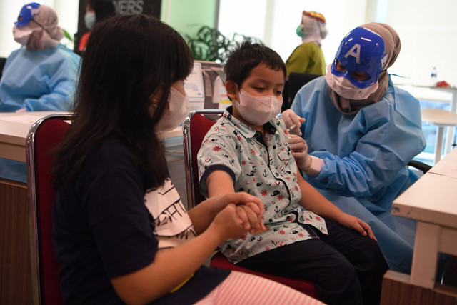 Tenaga kesehatan mengenakan topeng superhero saat menyuntikkan vaksin COVID-19 dosis kedua kepada seorang anak di Jakarta, Minggu (16/1).  Foto: Hafidz Mubarak A/ANTARA FOTO