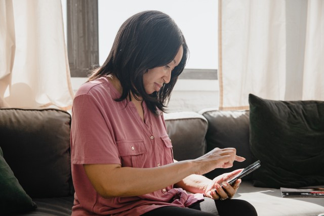 Ilustrasi seorang perempuan sedang membuka BRI mobile banking. Foto: Pexels.com