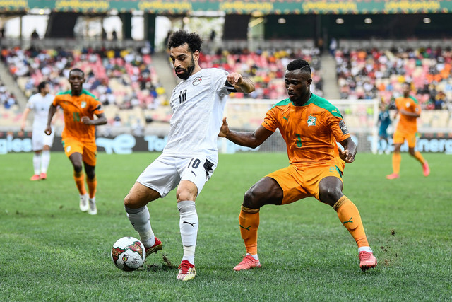 Pemain Mesir Mohamed Salah berusaha melewati pemain Pantai Gading Ghislain Konan pada pertandingan 16 besar Piala Afrika 2021 di Stadion Douala, Douala, Kamerun, Rabu (26/1/2022).  Foto: CHARLY TRIBALLEAU / AFP