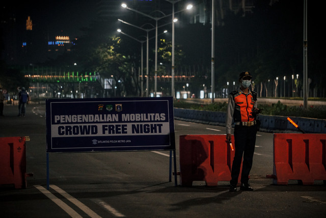 Petugas berjaga menghalau kendaraan yang melintas di Jalan Jenderal Sudirman saat Crowd Free Night Tahun Baru 2022 (1/1/2022). Foto: Jamal Ramadhan/kumparan