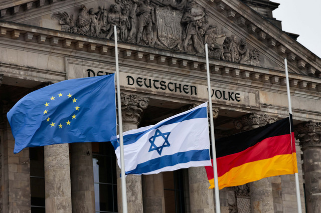 Bendera Israel, Jerman dan Uni Eropa terlihat di luar Parlemen Federal Jerman, Bundestag pada Hari Peringatan Holocaust Internasional, di depan gedung Reichstag, di Berlin, Jerman, 27 Januari 2022. Foto: REUTERS/Hannibal Hanschke