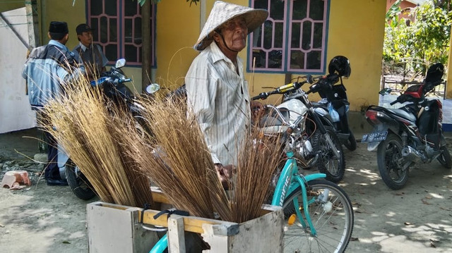 Kakek Tarimin (80), memenuhi kebutuhan hidup sehari-hari dengan berjualan sapu lidi buatan istrinya. Foto: Awal Dion/SulbarKini
