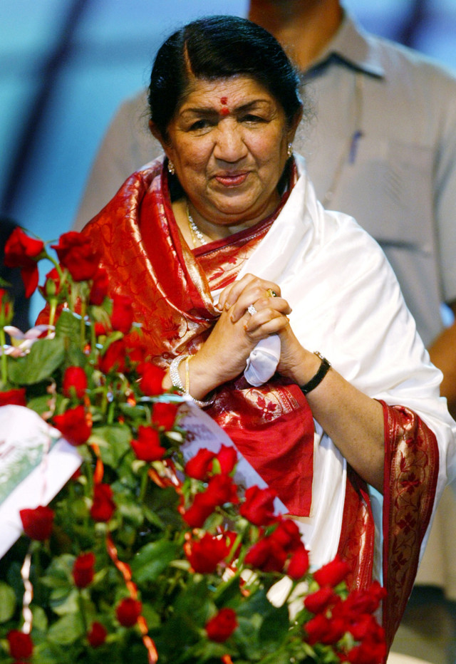 Penyanyi playback Bollywood Lata Mangeshkar melihat buket yang dia terima pada ulang tahunnya yang ke-75 selama perayaan di Bombay 28 September 2003. Foto: REUTERS/Sherwin Crasto