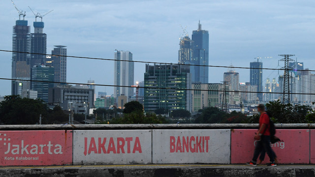 Warga melintas dengan latar belakang gedung bertingkat di kawasan Cideng, Jakarta, Rabu (9/2/2022). Foto: ANTARA FOTO/Wahyu Putro A