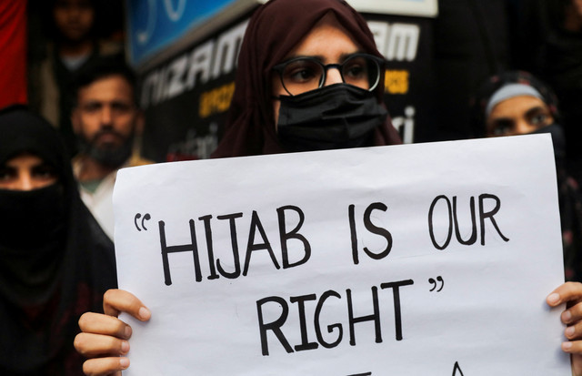 Massa memegang plakat saat protes terhadap larangan hijab di beberapa perguruan tinggi, di negara bagian Karnataka, di Shaheen Bagh di New Delhi, India, Rabu (9/2/2022). Foto: Anushree Fadnavis/REUTERS