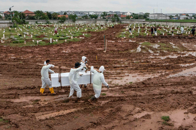 Sejumlah petugas mengusung peti jenazah pasien COVID-19 di TPU Rorotan, Jakarta, Kamis (10/2/2022). Foto: M Risyal Hidayat/ANTARA FOTO