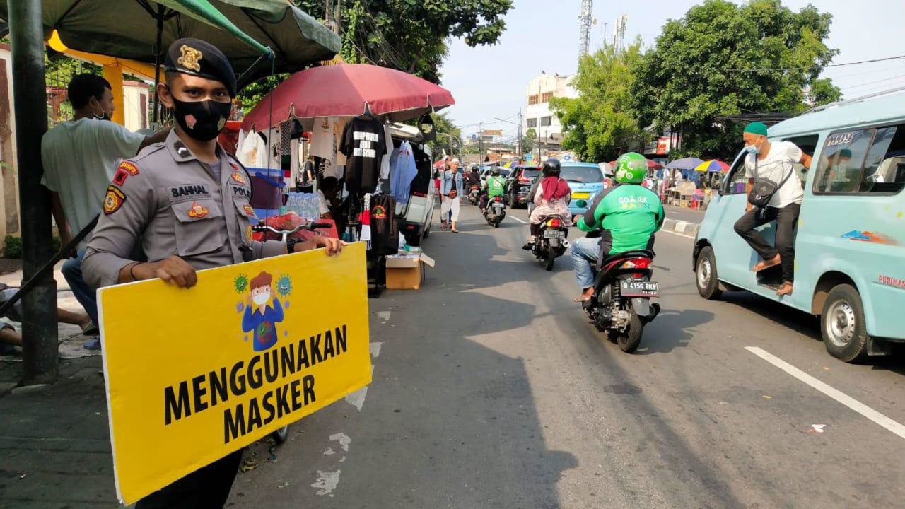 Personil Polres Jakarta Pusat dengan spanduk protokol corona