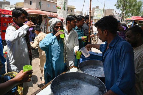 Penduduk desa bersama-sama meminum air yang disediakan oleh relawan selama gelombang panas di Jacobabad, di Sindh Selatan, Pakistan, Rabu (11/5/2022). Foto: Aamir Qureshi/AFP
