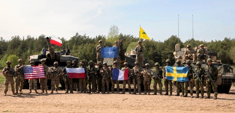 Tentara berpose saat foto bersama dengan NATO dan bendera nasional mereka selama latihan militer Defender Europe 2022 di Nowogrod, Polandia, Kamis (19/5/2022). Foto: Agnieszka Sadowska/Agencja Wyborcza.pl via Reuters