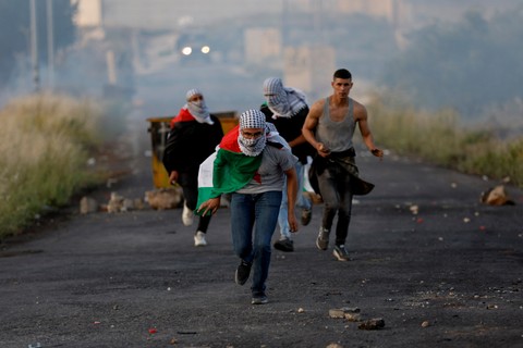 Orang-orang berlarian ketika warga Palestina bentrok dengan pasukan Israel selama protes atas ketegangan di Masjid Al-Aqsa Yerusalem. Foto: Mohamad Torokman/REUTERS