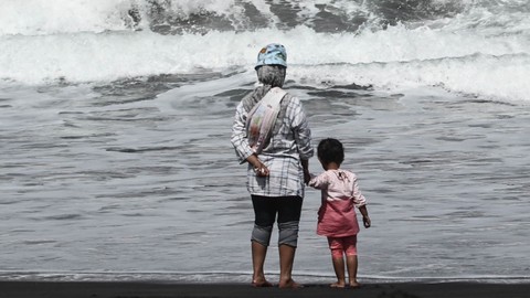 Seorang ibu memegangi anaknya yang bermain air di Pantai Cemoro Sewu, Parangtritis, Bantul, DI Yogyakarta, Selasa (31/5/2022). Foto: Hendra Nurdiyansyah/ANTARA FOTO