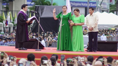 Wakil Presiden terpilih Filipina Sara Duterte (kiri)  mengambil sumpahnya di hadapan hakim agung Ramon Hernando didampingi ayahnya, Rodrigo Duterte, dan ibunya Elizabeth Zimmerman di balai kota di Kota Davao, Minggu (19/6/2022). Foto: Ferdinandh Cabrera / AFP