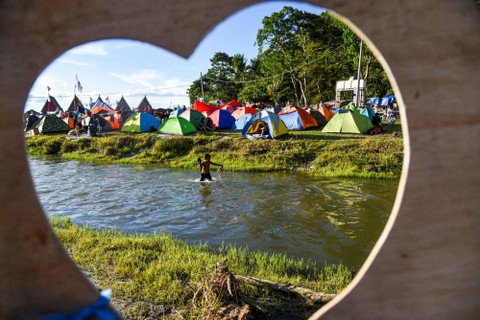 Seorang anak bermain di sungai saat mengikuti Festival 1000 Tenda Kaldera di Desa Meat, Balige, Toba, Sumatera Utara, Sabtu (25/6/2022). Foto: Fransisco Carolio/ANTARA FOTO