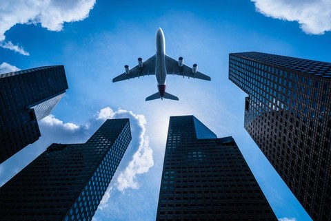 Ilustrasi pesawat yang sedang melintas di bangunan hotel. Foto: Shutter Stock