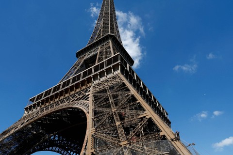Pekerja bekerja di menara Eiffel selama kampanye ke-20 pengecatan dan pengupasan di Paris, Prancis, Selasa (5/7/2022). Foto: Benoit Tessier/REUTERS
