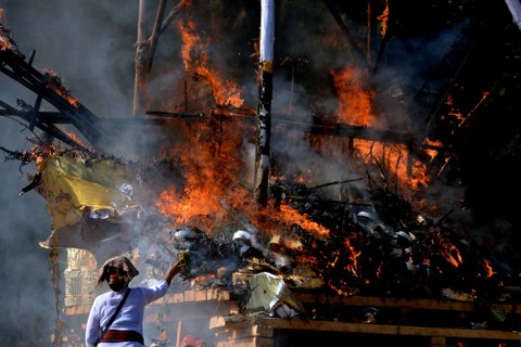 Warga menyaksikan prosesi kremasi saat upacara Ngaben massal di Desa Adat Padangbai, Karangasem, Bali, Jumat (29/7/2022). Foto: Fikri Yusuf/ANTARA FOTO