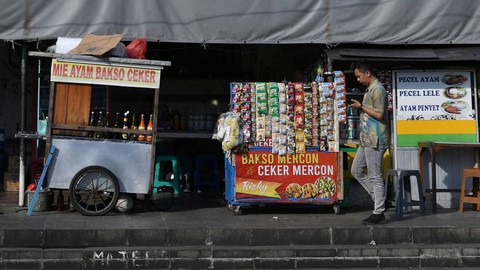 Warga melintasi tempat pedagang kaki lima (PKL) di salah satu sudut kawasan Kota Tua, Jakarta, Senin (1/8/2022). Foto: Aditya Pradana Putra/Antara Foto