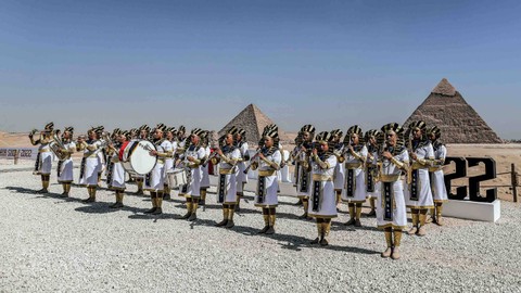 Anggota marching band yang mengenakan pakaian Mesir kuno tampil di awal Pyramids Air Show 2022. Foto: MAHMOUD KHALED/AFP