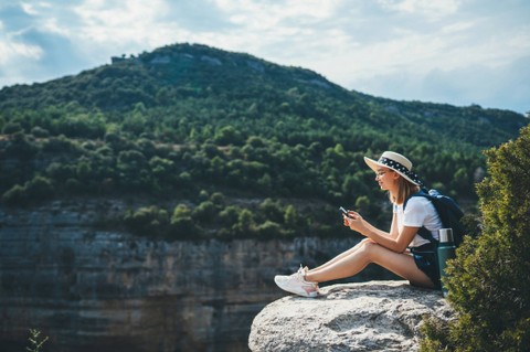 Ilustrasi traveler traveling di alam sambil membuka smartphone. Foto: A_B_C/Shutterstock