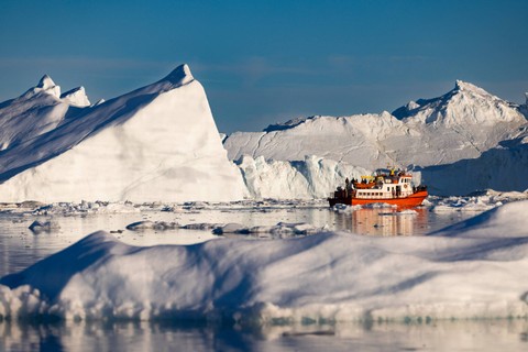 Sebuah kapal yang membawa wisatawan melakukan manuver di antara gunung es di Disko Bay, Ilulissat, Greenland barat, 1 Juli 2022. Foto: Odd Andersen/AFP