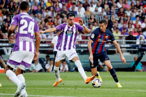 Pemain FC Barcelona Robert Lewandowski beraksi bersama pemain Real Valladolid Kike Perez di Stadion Camp Nou, Barcelona, Spanyol, Minggu (28/8/2022). Foto: Nacho Doce/REUTERS