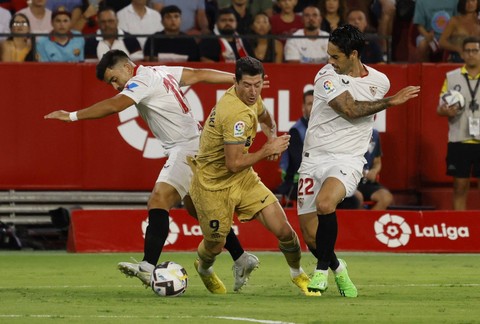 Marcos Acuna dan Isco dari Sevilla duel dengan Robert Lewandowski dari FC Barcelona saat pertandingan di Ramon Sanchez Pizjuan, Seville, Spanyol, Sabtu (3/9/2022). Foto: Marcelo Del Pozo/Reuters