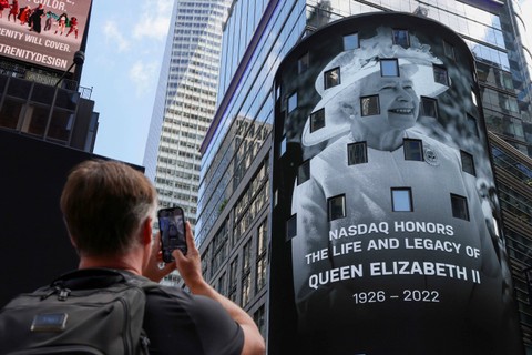 Seseorang mengambil foto sebagai penghormatan kepada Ratu Elizabeth II muncul di layar papan iklan Nasdaq MarketSite di Times Square, di New York, AS, Kamis (8/9/2022). Foto: Andrew Kelly/Reuters