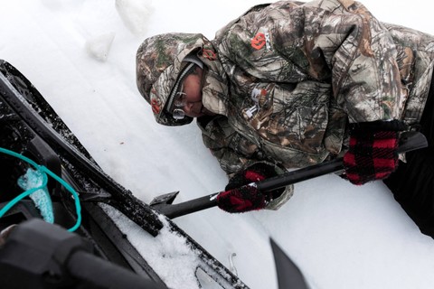 Maria Merkuratsuk (64) menggunakan kapak untuk menghilangkan es yang menumpuk di skidoo-nya, di Nain, Newfound and Labrador, Kamis (14/4/2022). Foto: Melissa Renwick/Reuters