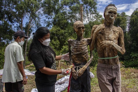 Kerabat membersihkan jenazah keluarganya saat ritual Manene di Lembang Ampang Batu, Kabupaten Toraja Utara, Sulawesi Selatan. Foto: Arnas Padda/Antara Foto