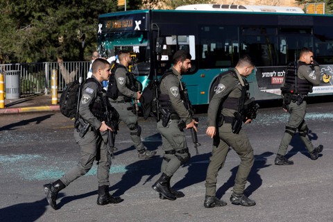 Polisi perbatasan Israel berjalan melewati bus yang rusak usai ledakan di halte bus di Yerusalem, Rabu (23/11/2022). Foto: Ammar Awad/REUTERS