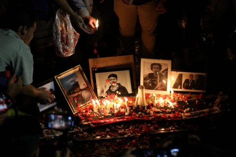 Massa mahasiswa menaburkan bunga di depan foto korban yang meninggal saat demo RKUHP pada tahun 2019 di sejumlah daerah saat unjuk rasa menolak RKUHP di DPR, Jakarta, Kamis (15/12/2022). Foto: Aditia Noviansyah/kumparan