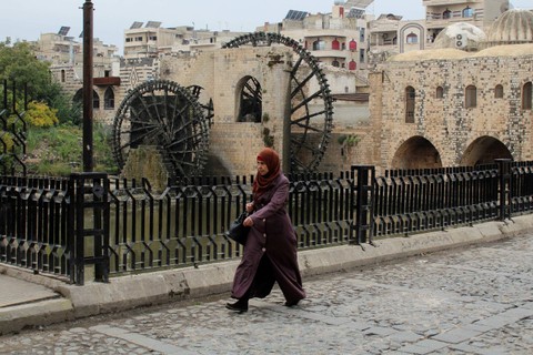 Warga berjalan di dekat kincir air di Hama, Suriah. Foto: Firas Makdesi/REUTERS