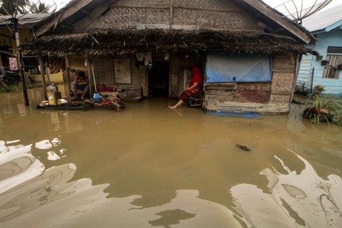 Warga duduk didepan rumah nya yang terendam di Desa Kumbang, Kecamatan Blang Mangat Lhokseumawe, Aceh, Rabu (21/12/2022). Foto: Rahmad/ANTARA FOTO