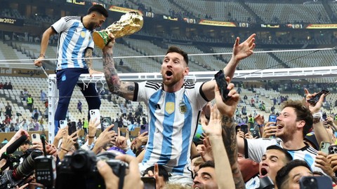 Pemain Argentina Lionel Messi memegang trofi Piala Dunia saat berselebrasi setelah memenangkan Piala Dunia 2022, di Stadion Lusail, Lusail, Qatar, Minggu (18/12/2022). Foto: Kai Pfaffenbach/REUTERS