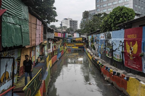 Warga berjalan di dekat mural di kawasan RW 03 Kelurahan Kampung Bali, Jakarta, Senin (26/12/2022). Foto: Aprillio Akbar/Antara Foto