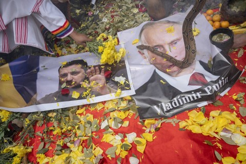 Dukun menampilkan poster Presiden Ukraina Volodymyr Zelensky dan Presiden Rusia Vladimir Putin saat melakukan ritual di puncak bukit di atas Lima, Peru, Rabu (28/12/2022). Foto: Cris Bouroncle/AFP
