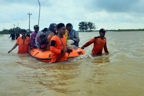 Personel BPBD membantu warga melintasi jalan yang terendam banjir dengan perahu karet di Dusun Karangturi, Setrokalangan, Kaliwungu, Kudus, Jawa Tengah, Senin (2/1/2023).  Foto: Fikri Yusuf/ANTARA FOTO