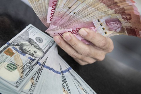 Petugas menunjukan uang pecahan rupiah dan dolar AS di gerai penukaran mata uang asing VIP (Valuta Inti Prima) Money Changer, Jakarta, Selasa (3/1/2023). Foto: Muhammad Adimaja/Antara Foto