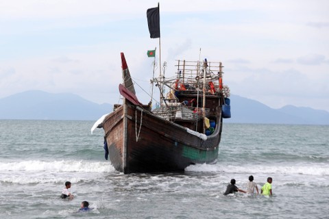 Sejumlah anak-anak bermain di dekat kapal kayu yang ditumpangi pengungsi suku Rohingya saat terdampar di pesisir pantai Kuala Gigieng, Aceh Besar, Aceh, Minggu (8/1/2023). Foto: ANTARA FOTO/Irwansyah Putra