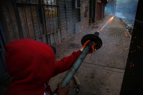 Seorang demonstran membidikkan kembang api selama protes menuntut pemilihan dini dan pembebasan pemimpin terguling Peru Pedro Castillo, di Juliaca, Peru 8 Januari 2023. Foto: Hugo Courotto/Reuters