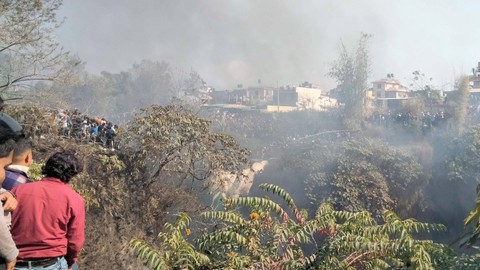 Massa berkumpul di lokasi jatuhnya pesawat yang membawa 72 orang di Pokhara di Nepal barat, Minggu (15/1/2023). Foto: Sagar Raj Timilsina/Handout via REUTERS