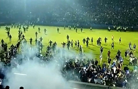 Tangkapan layar video AFPTV yang diambil pada 1 Oktober 2022 ini menunjukkan gas air mata di tengah orang-orang berlarian di lapangan usai pertandingan sepak bola antara Arema FC dan Persebaya Surabaya di Stadion Kanjuruhan, Malang, Jawa Timur. Foto: AFPTV