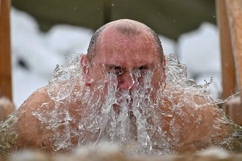 Seorang pria berendam di air es saat perayaan pesta Epifani Kristen Ortodoks di pemukiman Politotdel di wilayah Omsk, Rusia, Kamis (19/1/2023). Foto: Alexey Malgavko/REUTERS
