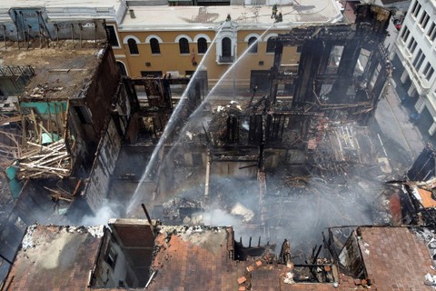 Petugas pemadam kebakaran bekerja di lokasi sebuah bangunan bersejarah terbakar, setelah ribuan demonstran protes di Lima, Peru, pada Jumat (20/1/2023). Foto: Angela Ponce/REUTERS